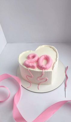 a heart shaped cake with pink frosting and sprinkles in the shape of donuts