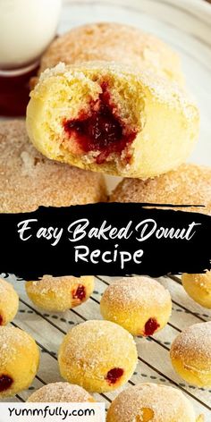 easy baked donut recipe with strawberry jam on top and in the background, there is a cooling rack full of doughnuts