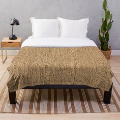 a bed sitting on top of a wooden floor next to a potted green plant