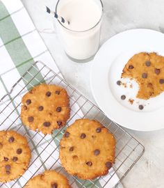 chocolate chip cookies cooling on a wire rack next to a glass of milk and a white plate