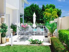 an outdoor patio with chairs, tables and potted plants on the side of it