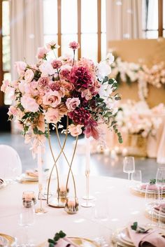 a vase filled with lots of pink flowers on top of a table next to plates