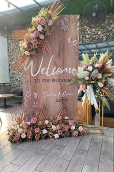 a welcome sign with flowers and greenery on it