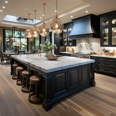 a large kitchen with black cabinets and marble counter tops