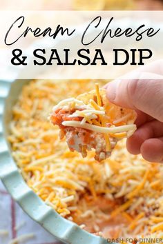 a hand holding up a piece of cheese and salsa dip from a casserole dish