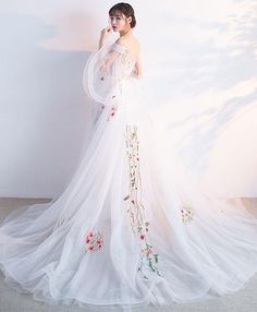 a woman in a white wedding dress with flowers on it