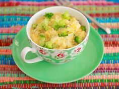 a green plate topped with a bowl of broccoli casserole next to a fork