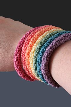 a woman's arm with four crocheted bracelets on it, all in different colors