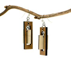 "These rectangular dangle earrings offer the boldness of a geometric design combined with the delicacy of a long, slender composition. The outer rectangle encompasses an inner panel for a multi-faceted design with movement and visual interest. Two tones of intricately cut wood - walnut and maple - give additional texture to the piece. Laser cut wood earrings can be dressed up or down, making them the perfect complement to any outfit! These earrings are strong but so lightweight and comfortable, Modern Dangle Chandelier Earrings As Gift, Modern Pierced Chandelier Earrings As Gift, Modern Gift Chandelier Earrings, Modern Dangle Earrings As Gift, Modern Dangle Earrings For Gifts, Brown Geometric Earrings Gift, Brown Geometric Earrings As Gift, Modern Dangle Plug Earrings As Gift, Modern Dangle Plug Earrings For Gift