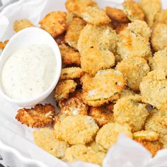 a white plate topped with fried food next to a bowl of ranch dressing