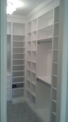 an empty walk in closet with white shelving