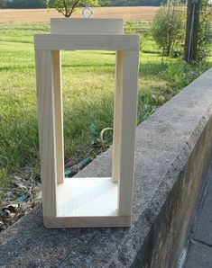 a wooden frame sitting on top of a cement wall next to a grass covered field