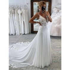 a woman taking a selfie in front of a mirror wearing a white wedding dress