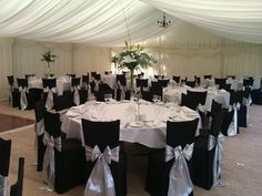 a banquet hall with black and white tables, chairs and bows on the tablecloths