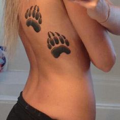 a woman is showing off her tattoo of two bears'paw prints on her chest