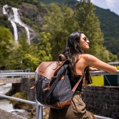 a woman with a backpack looking up at a waterfall