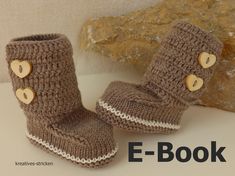 a pair of brown crocheted boots with hearts on them sitting next to a rock