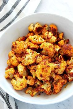 a white bowl filled with cooked cauliflower on top of a table