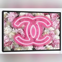 a chanel neon sign surrounded by pink and white peonies on a wall