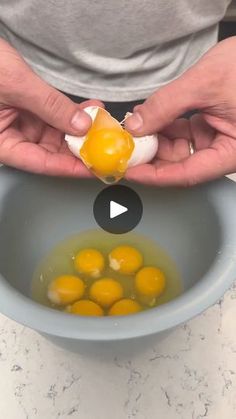 a person holding an egg in a bowl filled with water and eggs on top of it