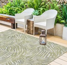 two white chairs sitting on top of a wooden floor next to a plant filled wall