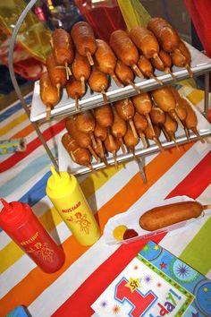 hot dogs and buns are being served on skewers at a birthday party