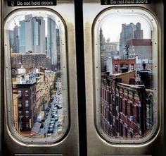 the view from inside an airplane window looking down on a city street with tall buildings