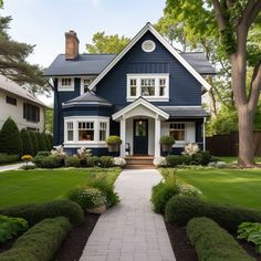 a blue house with white trim on the front and side windows is surrounded by lush green grass