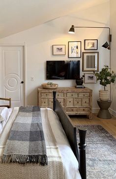 a bedroom with a bed, dresser and television