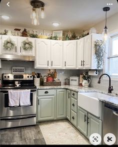 a kitchen with white cabinets and silver appliances in the center is decorated with greenery