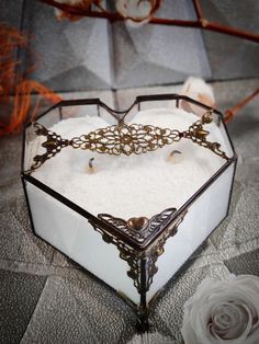 an ornate glass box filled with pearls and other jewelry sits on a table next to a white rose