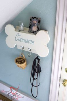 a dog bone shaped sign hanging on the wall next to a leash holder and other items