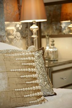 pillows and lamps on a bed in a room with white furnishing, gold trim