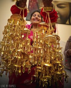 a woman is holding up some gold bells