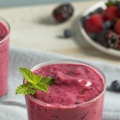 two glasses filled with berry smoothie on top of a table