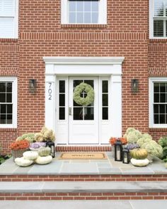 a brick house with pumpkins and gourds on the front steps