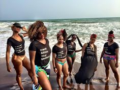 a group of women standing on top of a beach next to the ocean