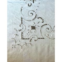 an embroidered piece of cloth with swirls and dots in the shape of letters e