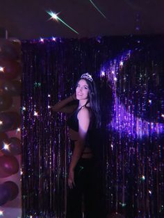 a woman standing in front of balloons and streamers with her arms behind her back