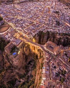 an aerial view of a city at night with lights on and mountains in the background