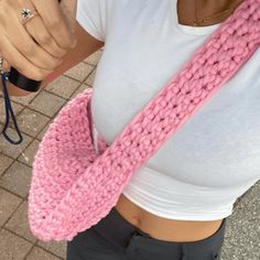 a woman wearing a pink knitted scarf around her neck and holding a cell phone