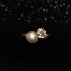 a pearl and diamond ring on a black background