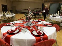 the table is set with red and white place settings, silverware, and christmas decorations