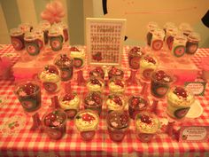 a table topped with lots of cupcakes covered in frosting and toppings