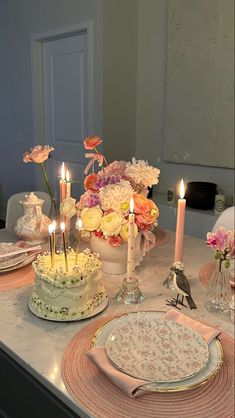 a table topped with cake and candles next to flowers on top of a white counter