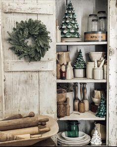 an old cupboard with christmas decorations and other items on it's shelves in a rustic kitchen