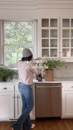 a woman standing in front of a kitchen sink next to a dishwasher and oven