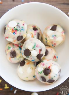 a white bowl filled with donuts covered in frosting and sprinkles