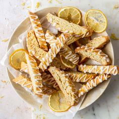 lemon scones with icing and sliced lemons in a bowl on a marble table