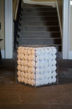 a box filled with white roses sitting on top of a floor next to a stair case